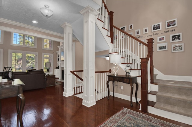 stairs with ornate columns, wood-type flooring, a high ceiling, ornamental molding, and french doors