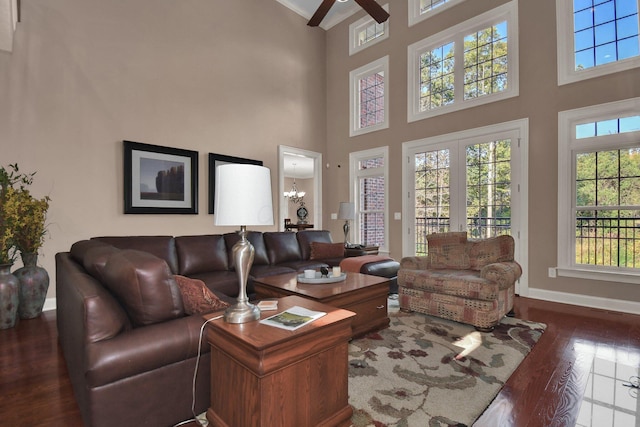 living room with ceiling fan with notable chandelier, hardwood / wood-style floors, and a high ceiling