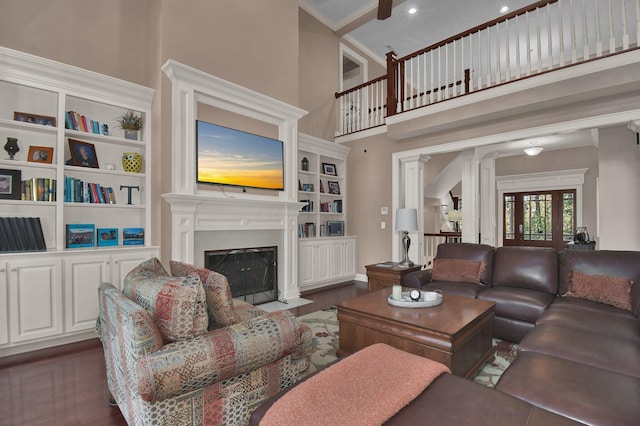 living room featuring dark wood-type flooring, built in features, decorative columns, and a high ceiling