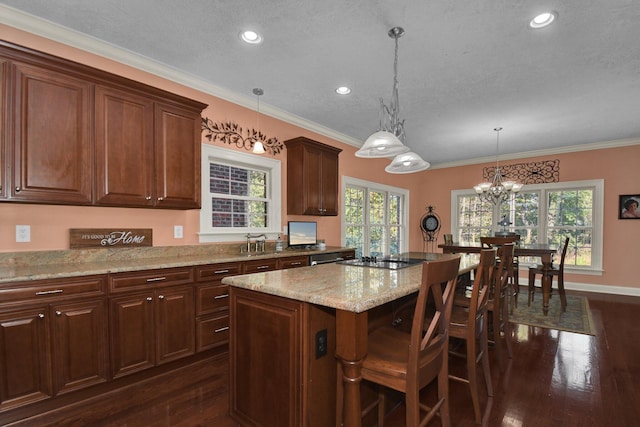 kitchen featuring pendant lighting, a center island, ornamental molding, a kitchen bar, and dark hardwood / wood-style flooring