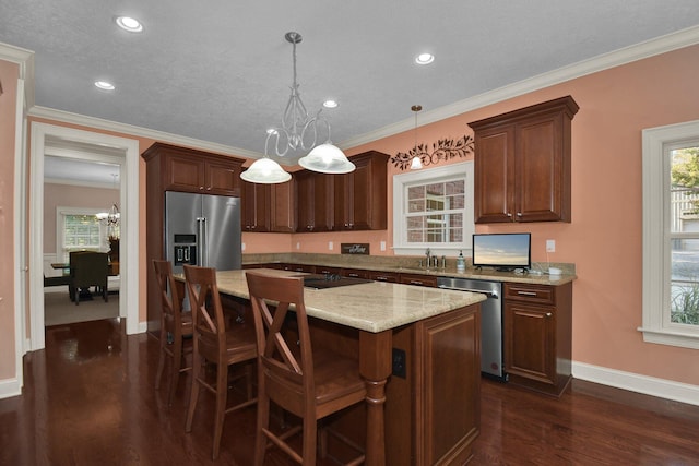 kitchen featuring pendant lighting, stainless steel appliances, a center island, a notable chandelier, and dark hardwood / wood-style flooring