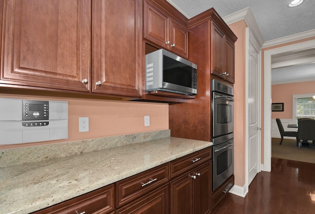 kitchen with crown molding, a textured ceiling, appliances with stainless steel finishes, dark hardwood / wood-style flooring, and light stone countertops