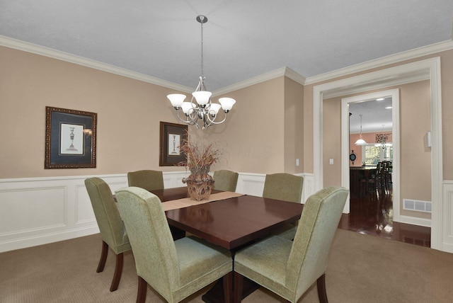 carpeted dining room featuring ornamental molding and an inviting chandelier