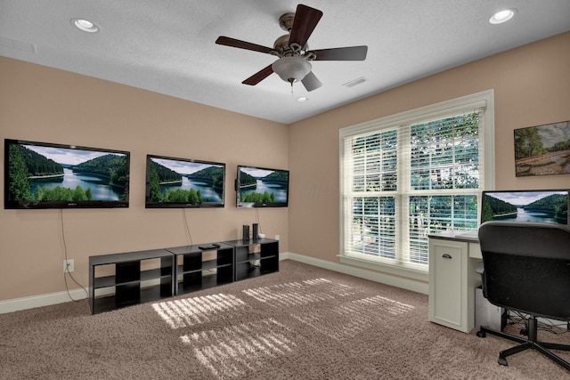 office space with a textured ceiling, light colored carpet, and ceiling fan