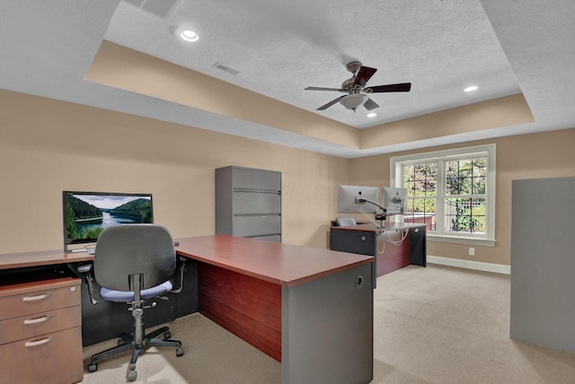 carpeted office space with a raised ceiling, ceiling fan, and a textured ceiling