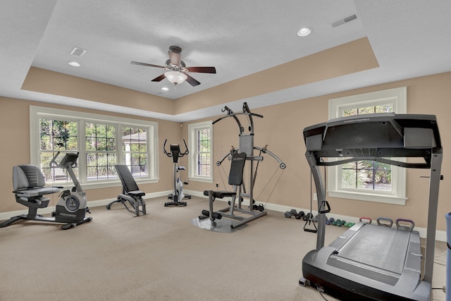 exercise area featuring ceiling fan and a tray ceiling