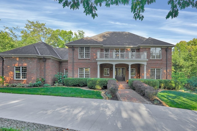 view of front of property with a front yard, a balcony, and covered porch