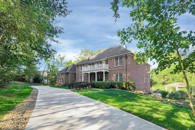 view of front facade featuring a front lawn and a balcony