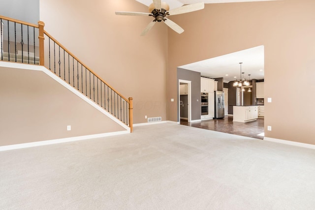 7873 Tullymore Dr, Dublin, OH 43016 - unfurnished living room with a towering ceiling, ceiling fan with notable chandelier, and dark colored carpet