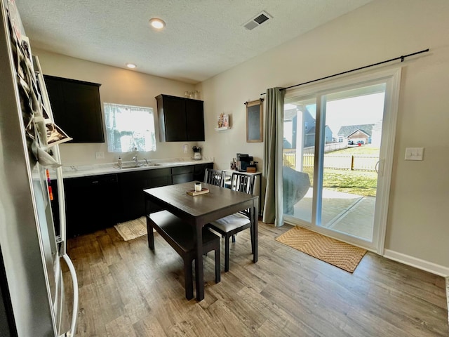 kitchen with sink, stainless steel fridge, a textured ceiling, and light hardwood / wood-style flooring