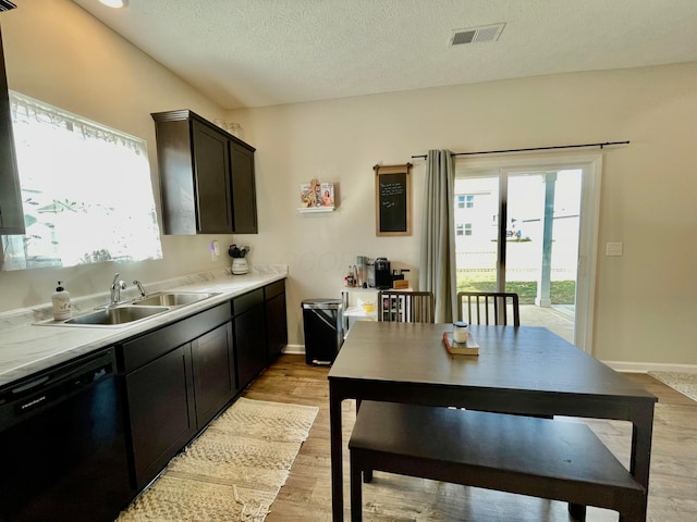 kitchen featuring sink, a textured ceiling, dark brown cabinets, light hardwood / wood-style flooring, and black dishwasher