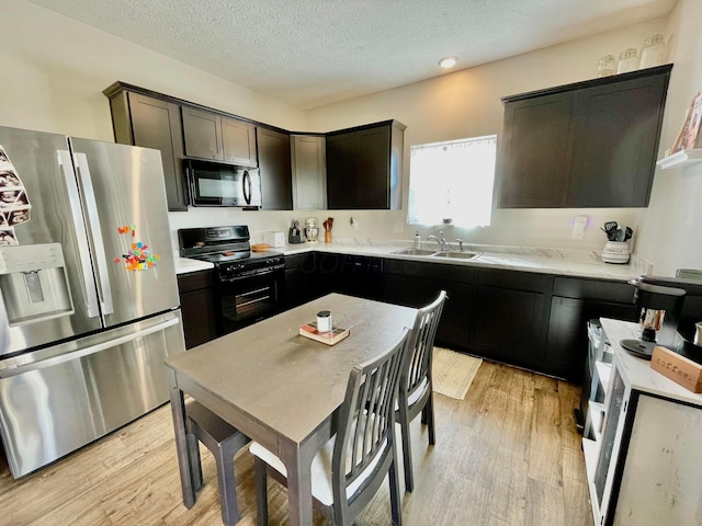 kitchen with dark brown cabinetry, sink, light hardwood / wood-style flooring, and black appliances