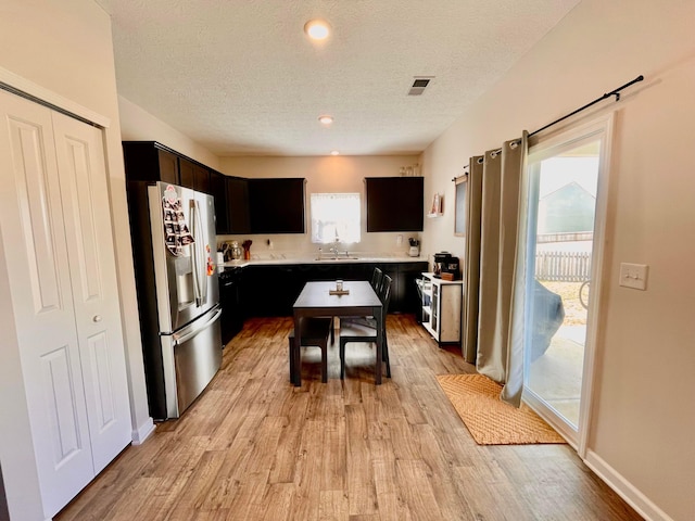 kitchen featuring stainless steel fridge with ice dispenser, light hardwood / wood-style floors, sink, and a textured ceiling