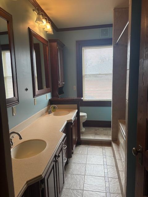 bathroom with vanity, crown molding, toilet, and a healthy amount of sunlight