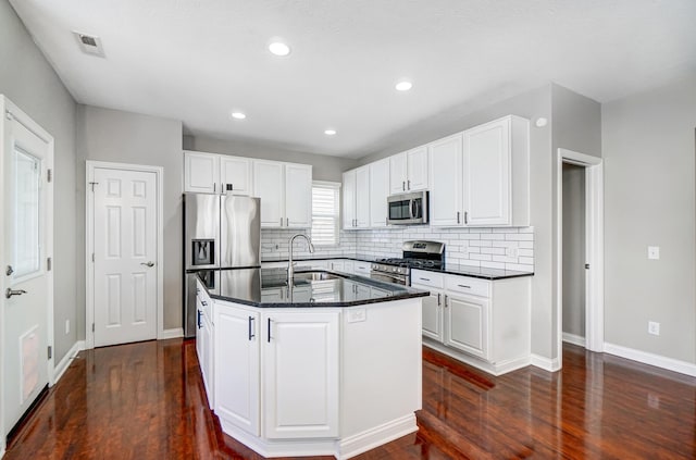 kitchen with sink, white cabinets, dark hardwood / wood-style flooring, stainless steel appliances, and a center island with sink