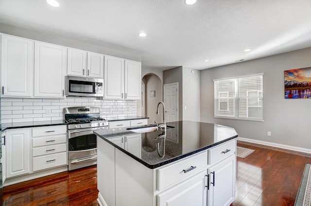 kitchen with sink, white cabinetry, tasteful backsplash, appliances with stainless steel finishes, and a kitchen island with sink