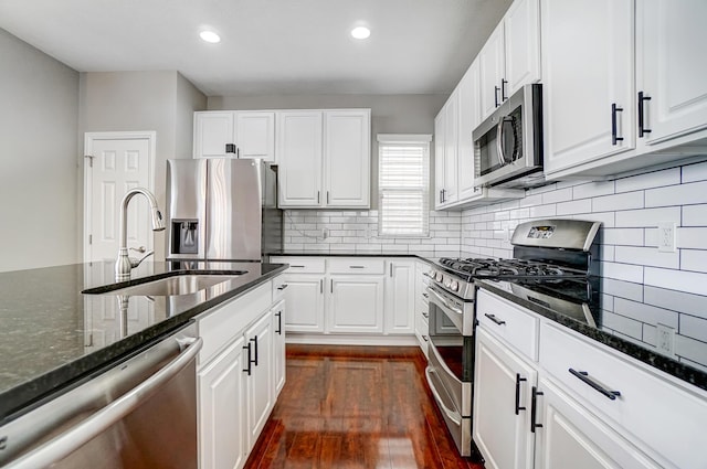 kitchen featuring white cabinetry, sink, stainless steel appliances, and dark stone counters