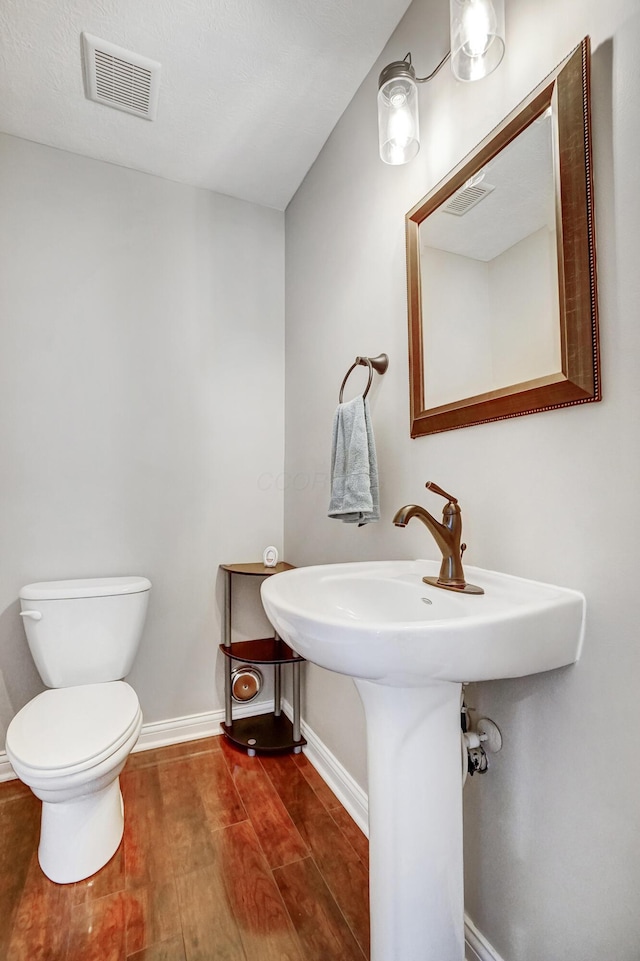 bathroom featuring wood-type flooring and toilet