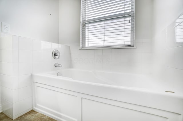 bathroom featuring tile walls and a tub