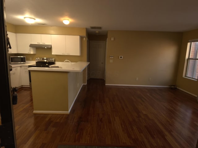 kitchen with appliances with stainless steel finishes, dark hardwood / wood-style floors, white cabinets, and kitchen peninsula