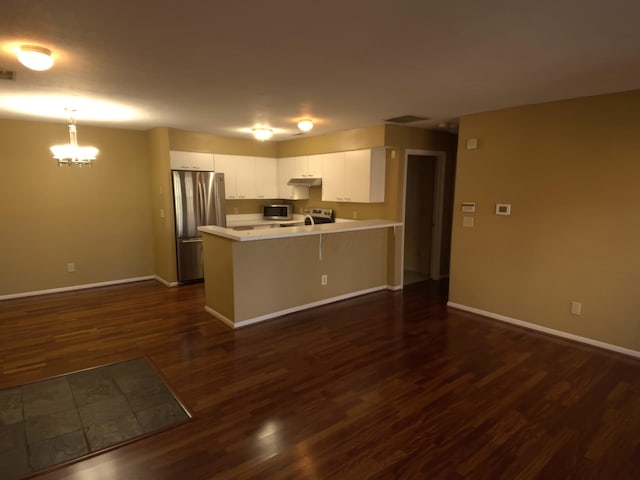 kitchen featuring pendant lighting, white cabinetry, a kitchen bar, stainless steel appliances, and dark wood-type flooring