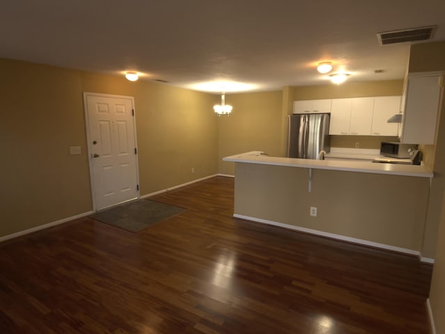 kitchen featuring appliances with stainless steel finishes, white cabinetry, a breakfast bar area, kitchen peninsula, and dark wood-type flooring