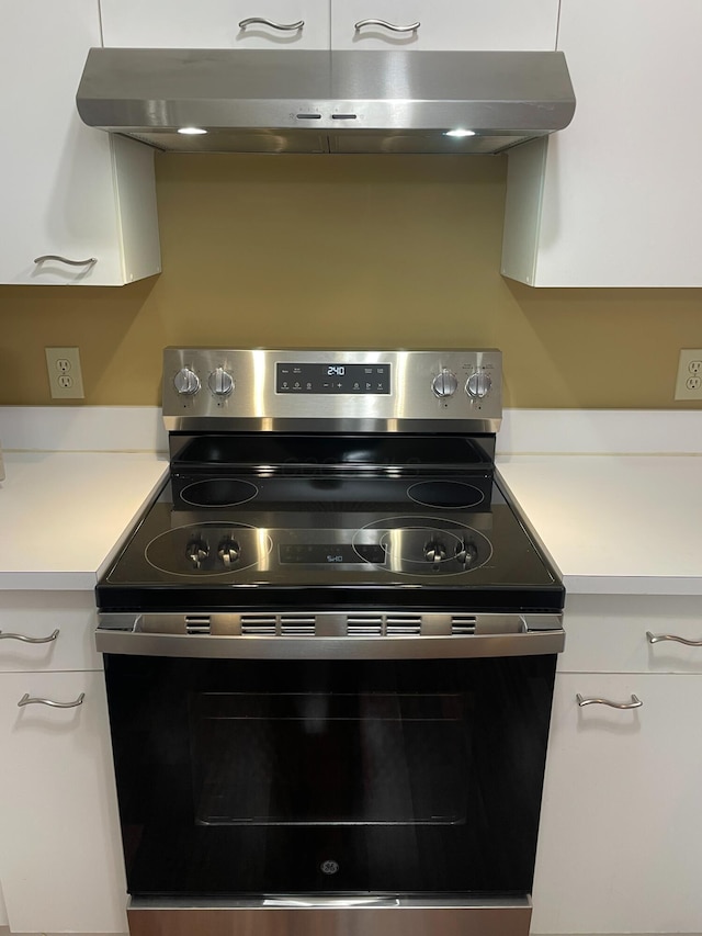 kitchen featuring stainless steel range with electric stovetop, exhaust hood, and white cabinets