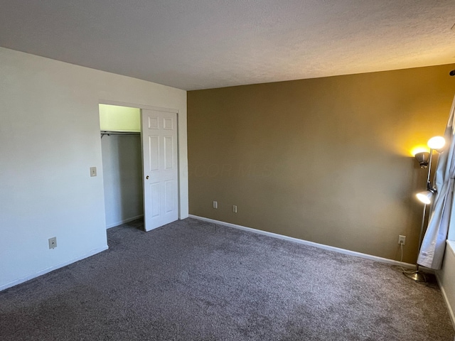 unfurnished bedroom featuring dark colored carpet, a textured ceiling, and a closet