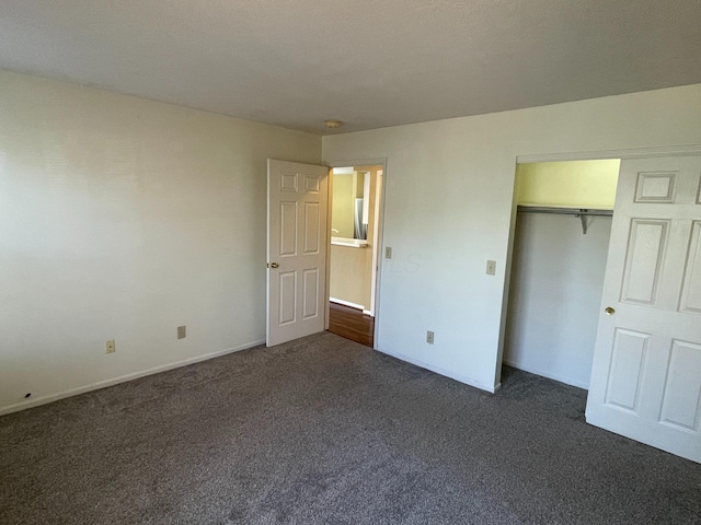 unfurnished bedroom with dark carpet and a closet