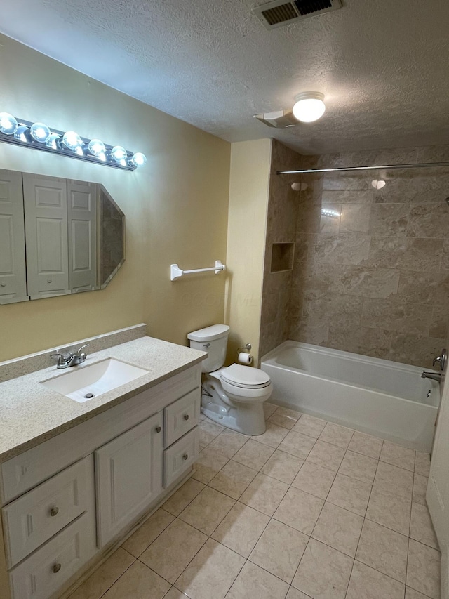 full bathroom featuring toilet, tiled shower / bath, a textured ceiling, vanity, and tile patterned flooring