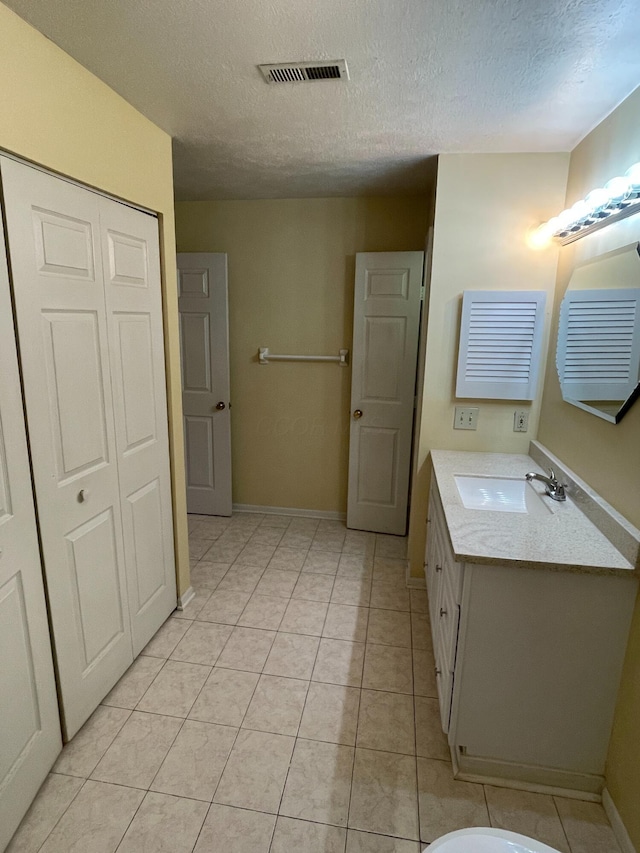 bathroom featuring tile patterned flooring, vanity, and a textured ceiling