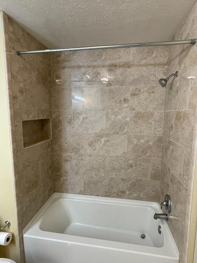 bathroom with tiled shower / bath combo, toilet, and a textured ceiling