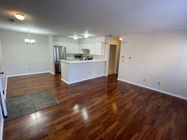 kitchen featuring visible vents, under cabinet range hood, appliances with stainless steel finishes, a peninsula, and dark wood-style floors