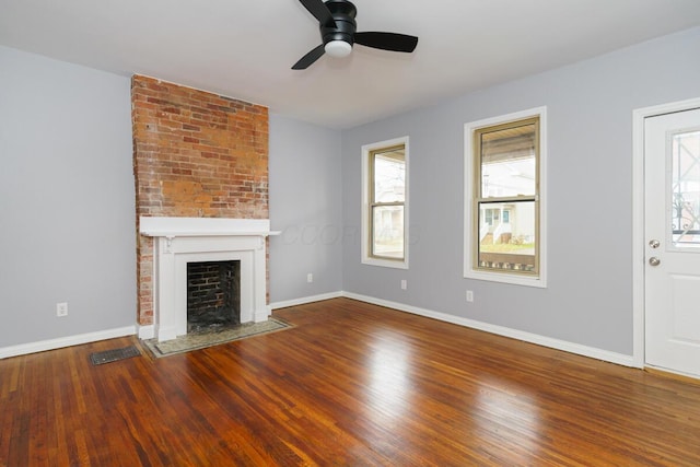 unfurnished living room with wood-type flooring, a large fireplace, and ceiling fan