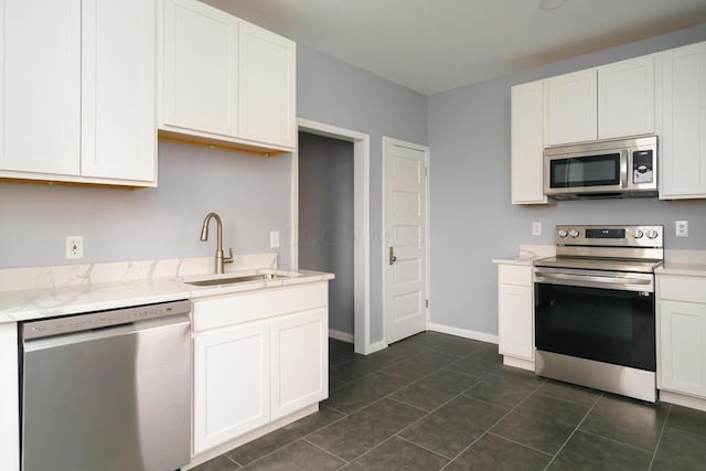 kitchen with dark tile patterned floors, appliances with stainless steel finishes, sink, and white cabinets