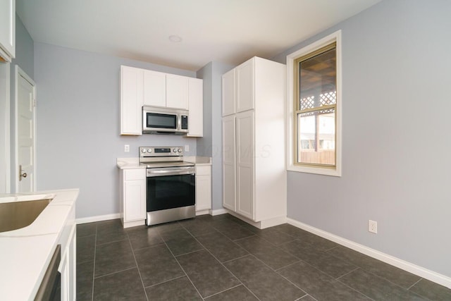 kitchen featuring white cabinetry, sink, stainless steel appliances, and dark tile patterned floors