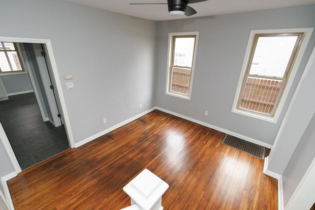 spare room with ceiling fan, dark wood-type flooring, and a healthy amount of sunlight