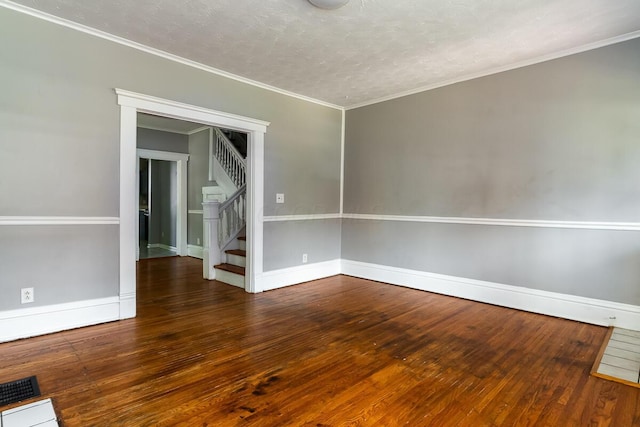 empty room with dark hardwood / wood-style flooring, ornamental molding, and a textured ceiling