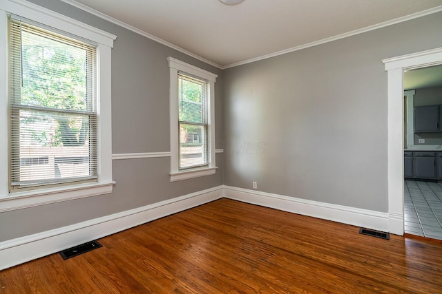 empty room featuring ornamental molding, a baseboard heating unit, and hardwood / wood-style floors