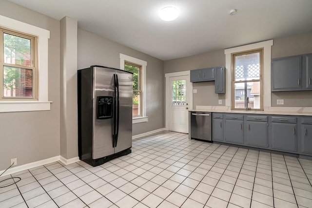 kitchen with stainless steel appliances, gray cabinets, and light tile patterned floors