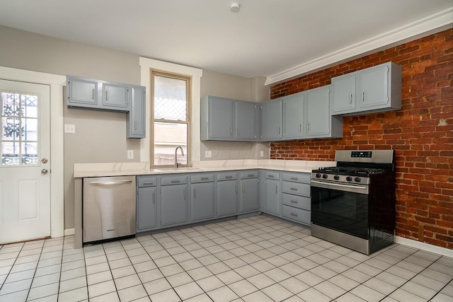 kitchen with brick wall, appliances with stainless steel finishes, sink, and plenty of natural light