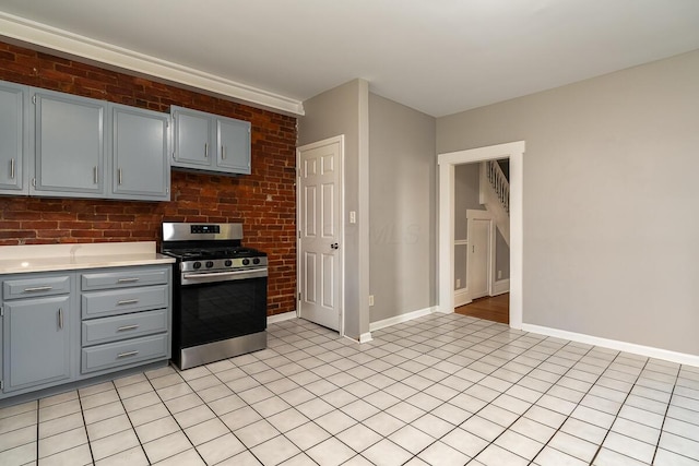 kitchen with brick wall, stainless steel gas range, and gray cabinetry