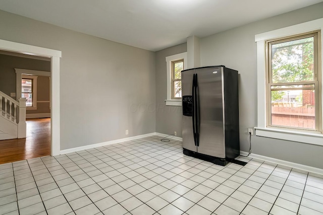 kitchen with stainless steel refrigerator with ice dispenser, a healthy amount of sunlight, and light tile patterned floors