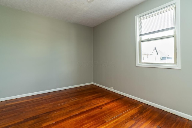 spare room featuring dark wood-type flooring and a textured ceiling