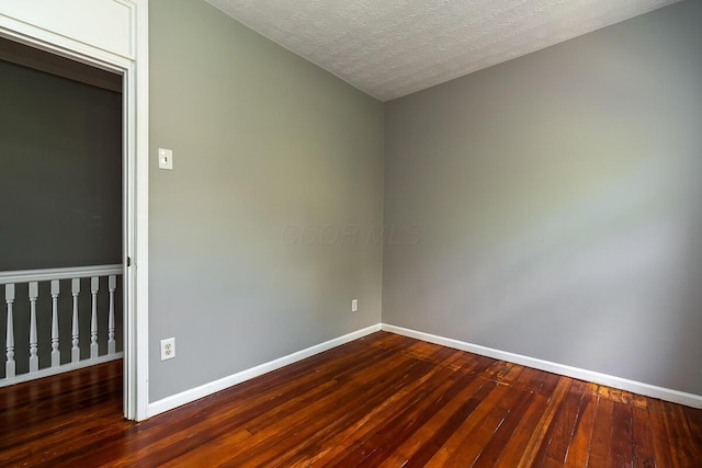 spare room with dark wood-type flooring and a textured ceiling