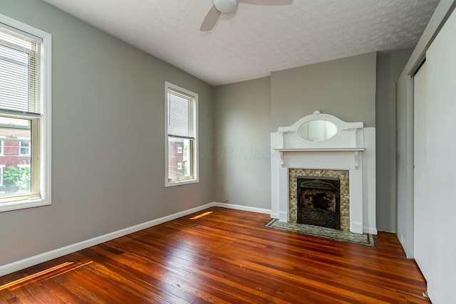 unfurnished living room featuring a fireplace, dark wood-type flooring, a textured ceiling, and ceiling fan