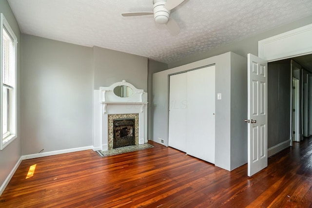 unfurnished living room featuring ceiling fan, plenty of natural light, dark hardwood / wood-style floors, and a textured ceiling