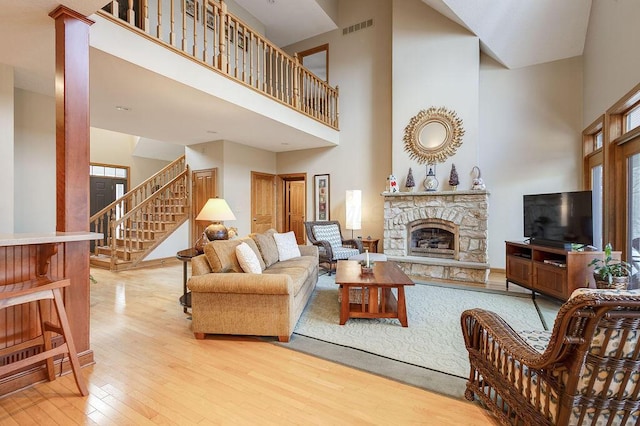 living room with a fireplace, a high ceiling, and light wood-type flooring