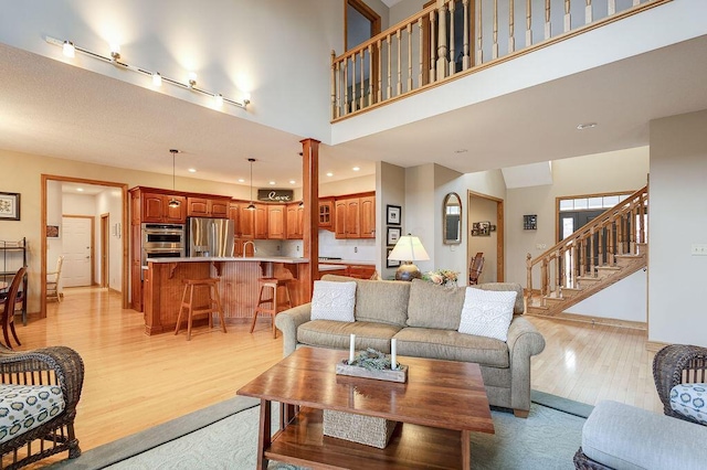 living room featuring ornate columns, a high ceiling, and light wood-type flooring