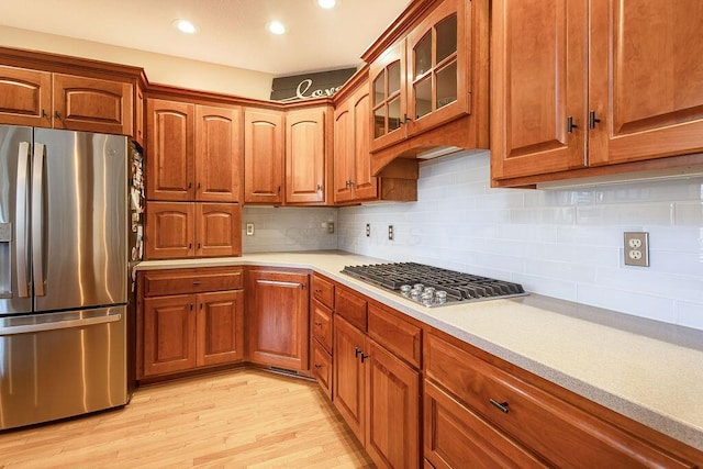 kitchen with stainless steel appliances, light wood-type flooring, and decorative backsplash